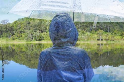 Double Exposure image of a person holding an umbrella and a reservoir reflecting the mountains.