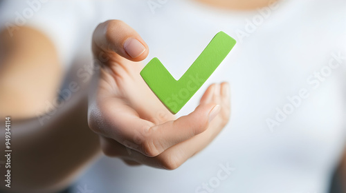 Hand holding a green check mark symbol.