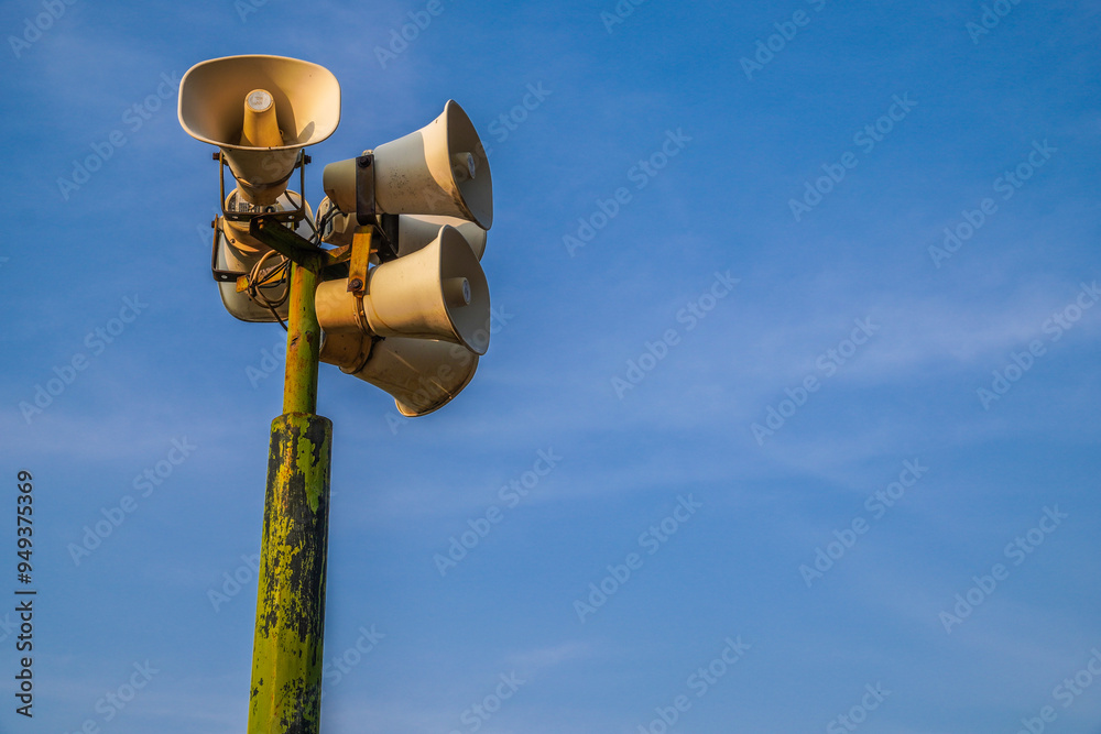 Loudspeaker on pole, alarm siren on blue sky background. public speaker system loudspeakers on blue sky background with copy space. Loudspeaker on pole, alarm siren on blue sky background. public speaker system loudspeakers on blue sky background with copy space.