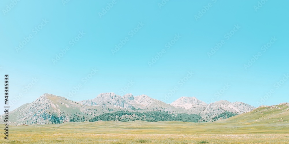 Fototapeta premium Mountain Range Landscape with Grassy Meadow and Clear Blue Sky