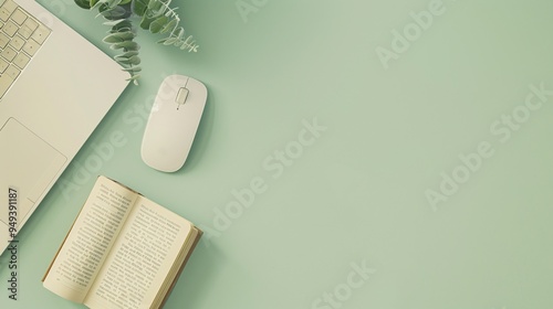 07231249 159. Creative flat lay photo of a modern workspace including a keyboard, mouse, and an open book on a pastel green backdrop, showcasing simplicity and elegance