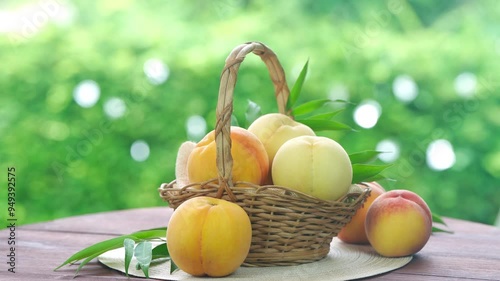 Fresh three kinds of peaches on blurred greenery background, Three colored peaches in basket on wooden table in garden.