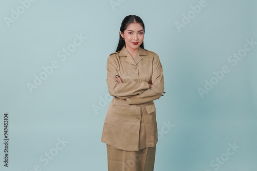 Confident government worker woman wearing khaki uniform smiling and standing with her arms crossed.