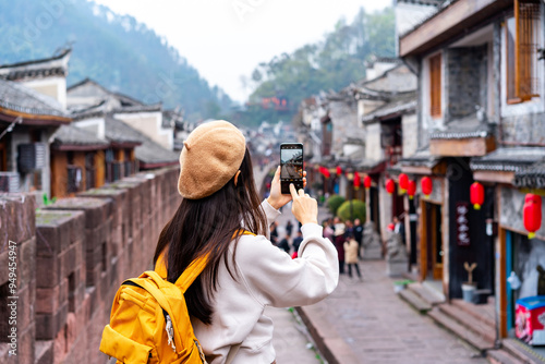 Young female tourist taking a photo of the Feng Huang Ancient Town, The famous tourist destination at Hunan Province, China photo