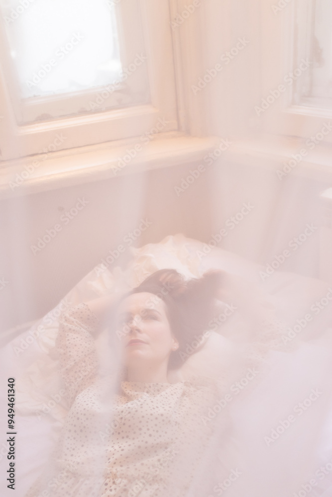 Morning of beautiful young woman lying in bed and streching. Girl in dress waking up under canopy in bedroom. Light vertical shot of sleeping beauty. Dreaming lady Morning of beautiful young woman lying in bed and streching. Girl in dress waking up under canopy in bedroom. Light vertical shot of sleeping beauty. Dreaming lady