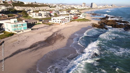 Aerial tilt-up reveals scenic Bloubergstrand shoreline near Cape Town at sunset photo