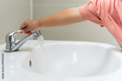 Save water. Little kid keeps turning off the running water in the bathroom to protect environment. Greening planet, reduce global warming, Save world, life, future, risk energy, crisis , water day.. photo