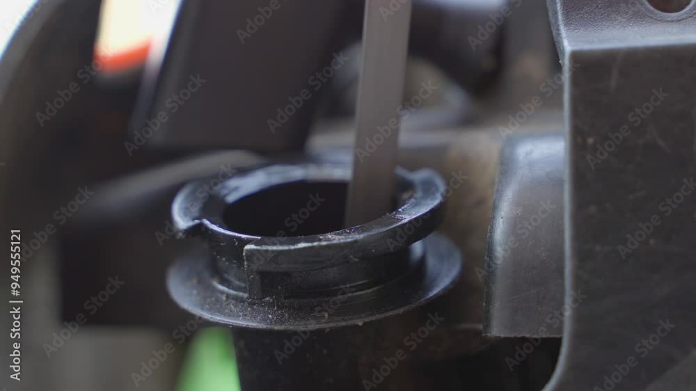A hand pulls out the lawnmower oil dipstick and checks the oil level close-up A hand pulls out the lawnmower oil dipstick and checks the oil level close-up