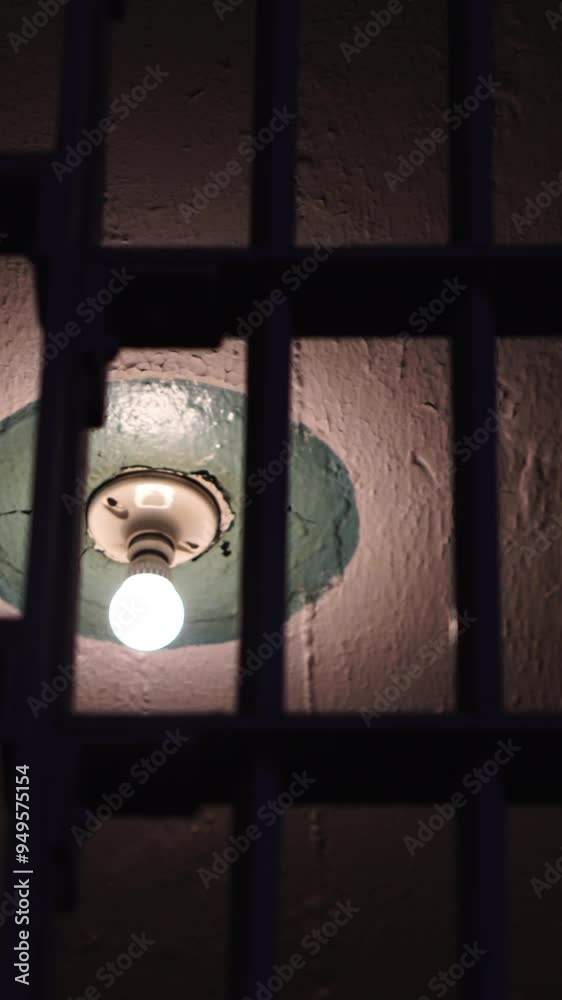 Vertical View, Prison Cell in Alcatraz Federal Penitentiary at Night, Ceiling and Light Bulb View Behind Bars, California USA