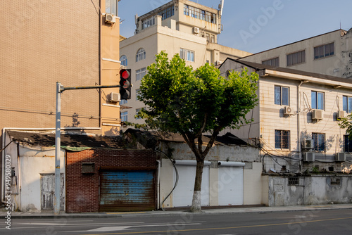 An urban street corner in an Asian country with a traffic light and a mix of older, aging buildings with worn-out façades and closed shops.A sense of neglect and decline in the urban area.Ningbo,China