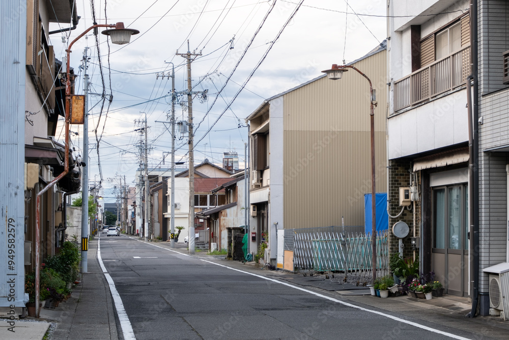 A narrow and quiet Japanese residential street, lined with two-story old and weathered houses. Peaceful neighbourhood with aging modest buildings. Gifu, Japan A narrow and quiet Japanese residential street, lined with two-story old and weathered houses. Peaceful neighbourhood with aging modest buildings. Gifu, Japan