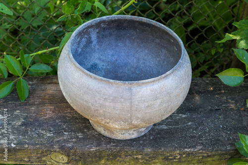 Outdated old bell-shaped metal pot on dark wooden surface