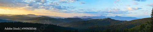 Sun rising over the Carpathian mountains; panoramic view. Silhouettes of mountain peaks; morning fog drifts over the mountains.