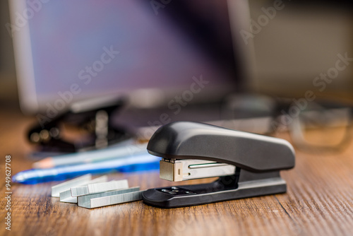 Black office stapler on wooden table.