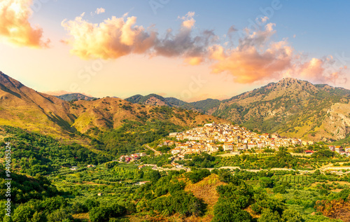 amazing mountain landscape with old yellow italian town among green beatiful mountains and cloudy sky above