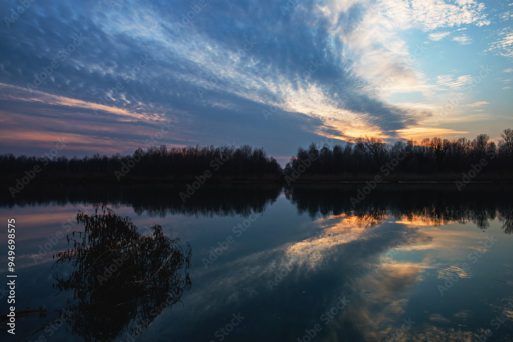 tramonto in controluce sul fiume, che si riflette sull'acqua, insieme a tante grandi nuvole che coprono il cielo tramonto in controluce sul fiume, che si riflette sull'acqua, insieme a tante grandi nuvole che coprono il cielo