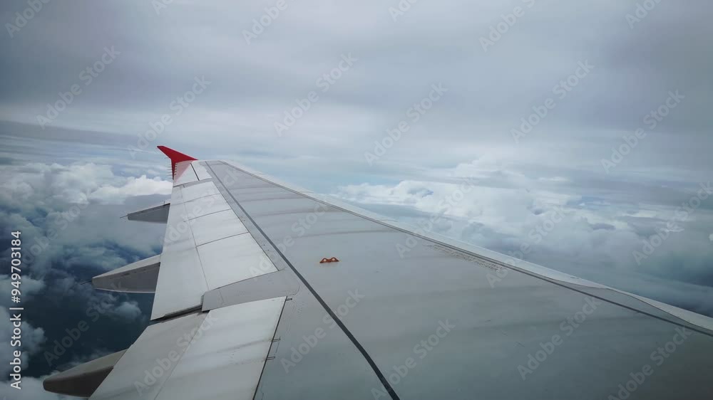 The airplane's wings during the flight look from the passenger window, and gray clouds gather in the sky before the rainstorm.