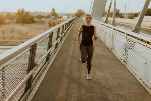 Determined runner jogs along a sunlit bridge during the golden hour, blending fitness and serenity in an urban landscape