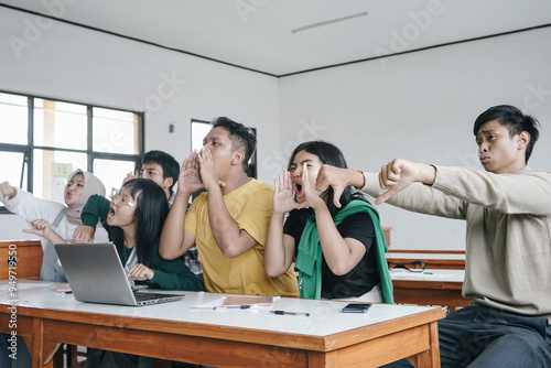 Foto Asian students teasing and judging their classmate in classroom