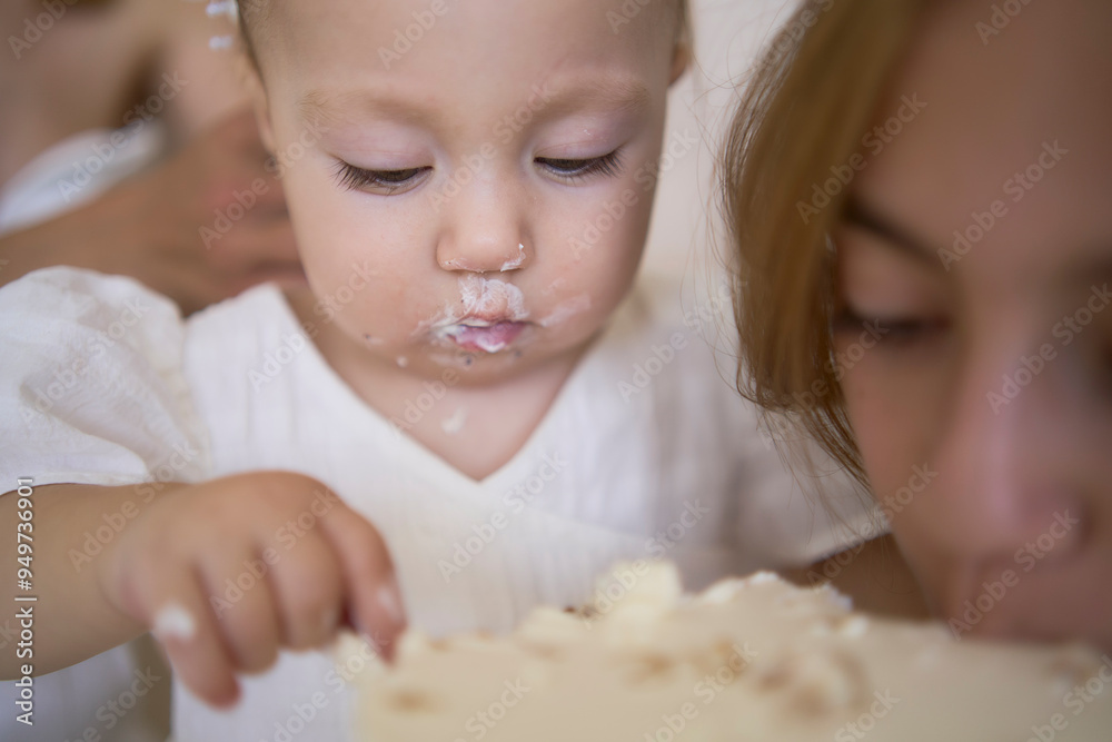baby girl tries her first birthday cake with mom and pre-teen sister baby girl tries her first birthday cake with mom and pre-teen sister
