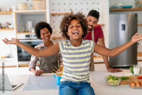 Overjoyed young african american family with kid have fun cooking at home together, photo