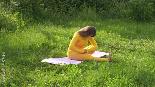 Woman makes yoga exersices outdoor. Healthy lifestyle activity in the park at the morning photo