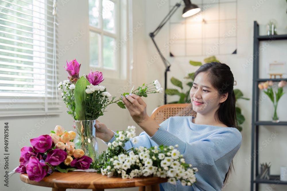 Asian woman creatively arranging flowers in vase at home Asian woman creatively arranging flowers in vase at home