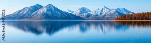 Tranquil mountain lake with snow-capped peaks reflecting in the water