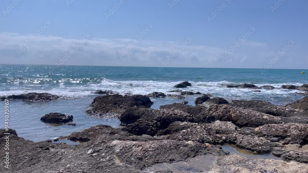 Waves crash against rocks at beach, sea spray in air, sunlight reflects on water. Natural ocean wave motion, hit rough stone coast in evening. Nature scene for calm, travel, atmosphere. 4k footage Waves crash against rocks at beach, sea spray in air, sunlight reflects on water. Natural ocean wave motion, hit rough stone coast in evening. Nature scene for calm, travel, atmosphere. 4k footage
