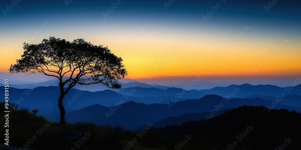 Fototapeta premium Tree silhouette against a stunning sunset over mountain peaks.