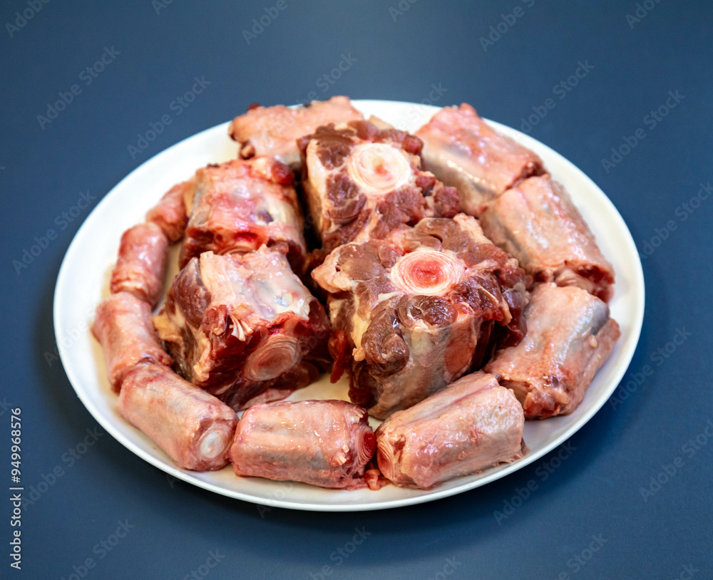 Raw beef oxtail on a round white plate in closeup. Raw beef oxtail on a round white plate in closeup.