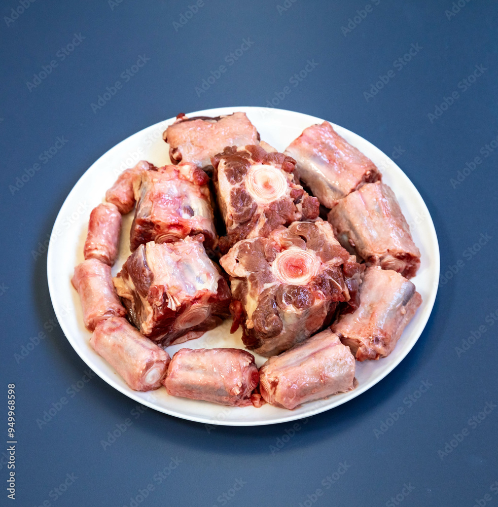 Raw beef oxtail on a round white plate in closeup. Raw beef oxtail on a round white plate in closeup.