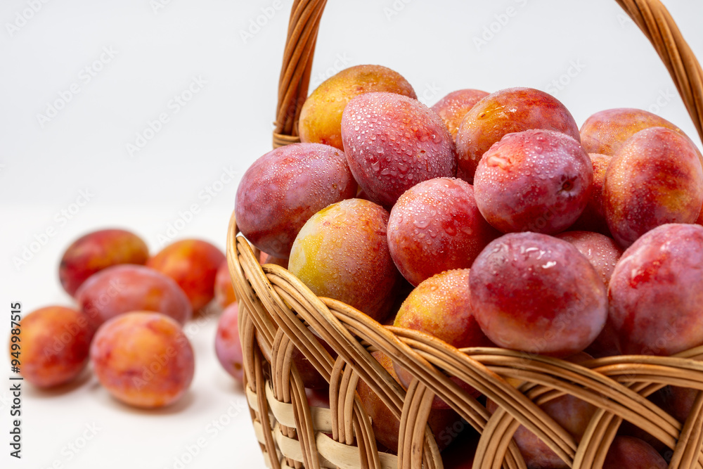 Beautiful ripe sweet plums in a basket isolated on white background. Close up.