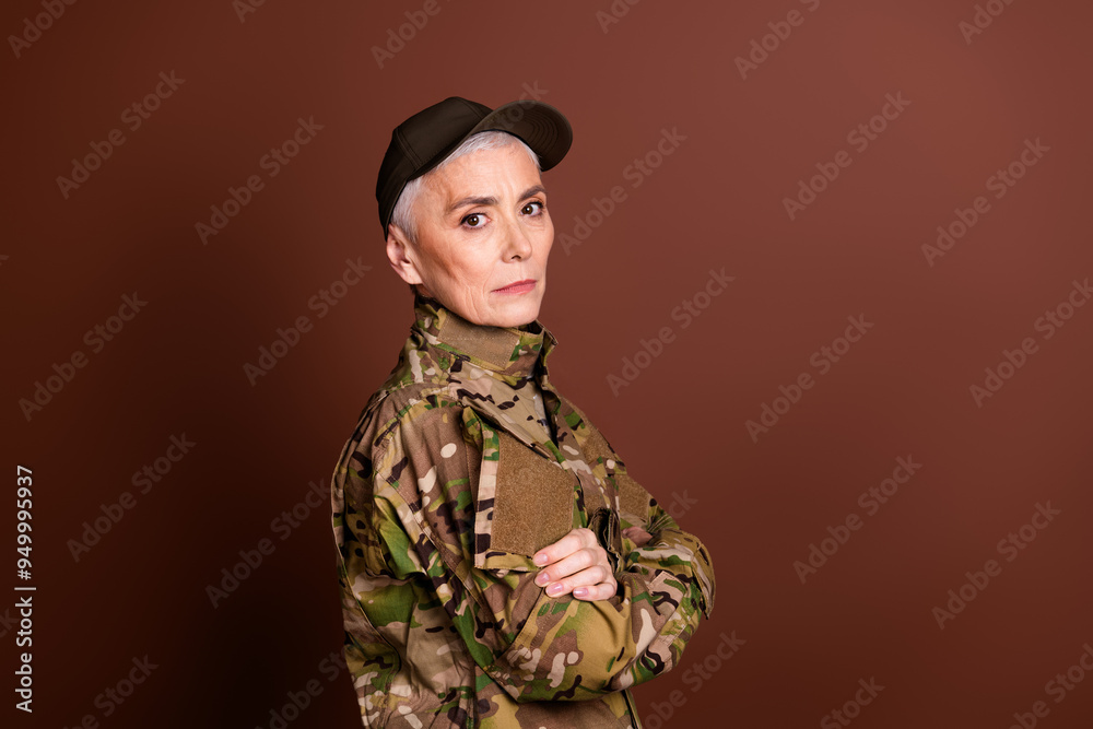 Photo of military serious senior woman wear camouflage arms crossed empty space isolated brown color background Photo of military serious senior woman wear camouflage arms crossed empty space isolated brown color background