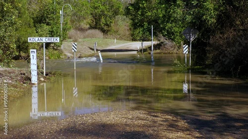 Flooded flooding creek stream river, water over road, dangerous strong current, traffic hazard, climate change, Kolan Queensland Australia