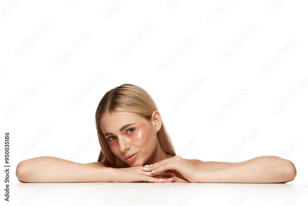 Beautiful young blonde woman with flawless, clear skin applying under eye patches isolated on white background. Natural beauty and benefits of advanced skincare. Concept of beauty, skincare, cosmetics Beautiful young blonde woman with flawless, clear skin applying under eye patches isolated on white background. Natural beauty and benefits of advanced skincare. Concept of beauty, skincare, cosmetics