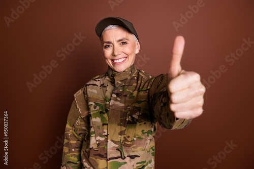 Photo of strong positive elderly lady dressed camo uniform showing you thumb up empty space isolated brown color background
