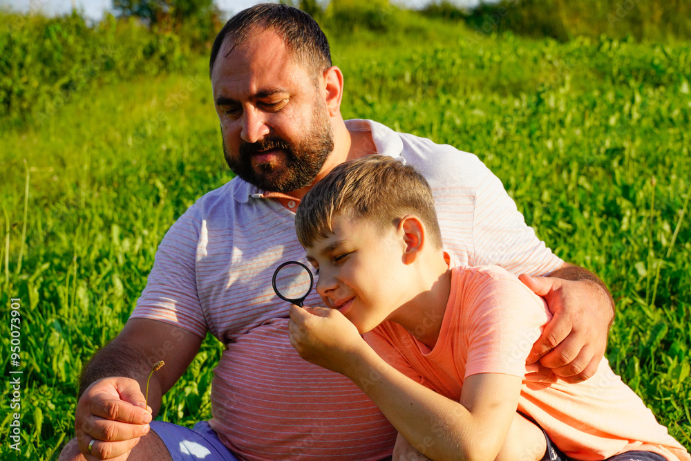 Father and sons exploring nature, looking at plants insects though magnifying glass Father and sons exploring nature, looking at plants insects though magnifying glass