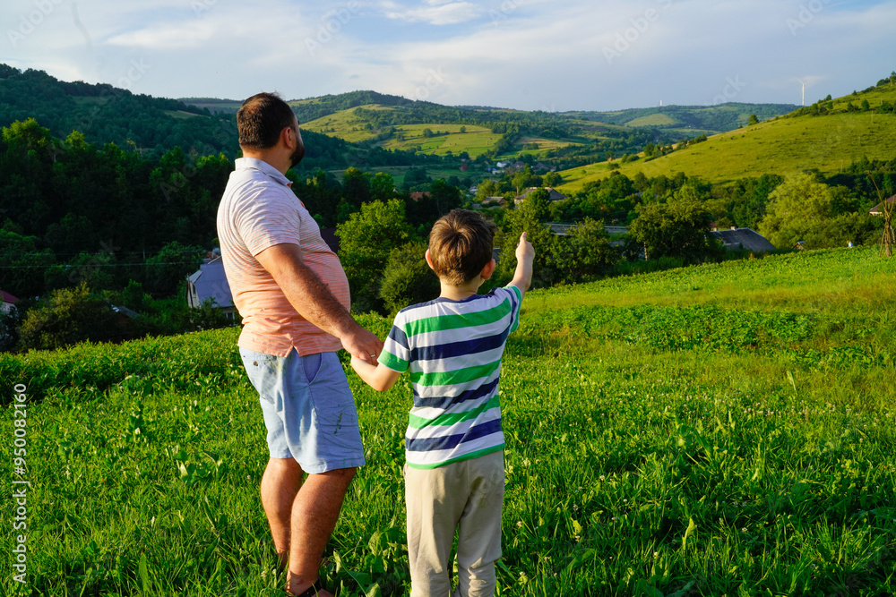 Father and son enjoying sunset at the meadow in mountains Father and son enjoying sunset at the meadow in mountains