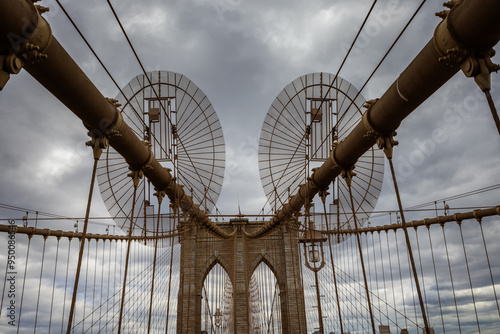 Iconic Bridge with Dramatic Sky. Photo of a famous bridge with towering archways and steel cables set against a cloudy, dramatic sky captured during daytime.