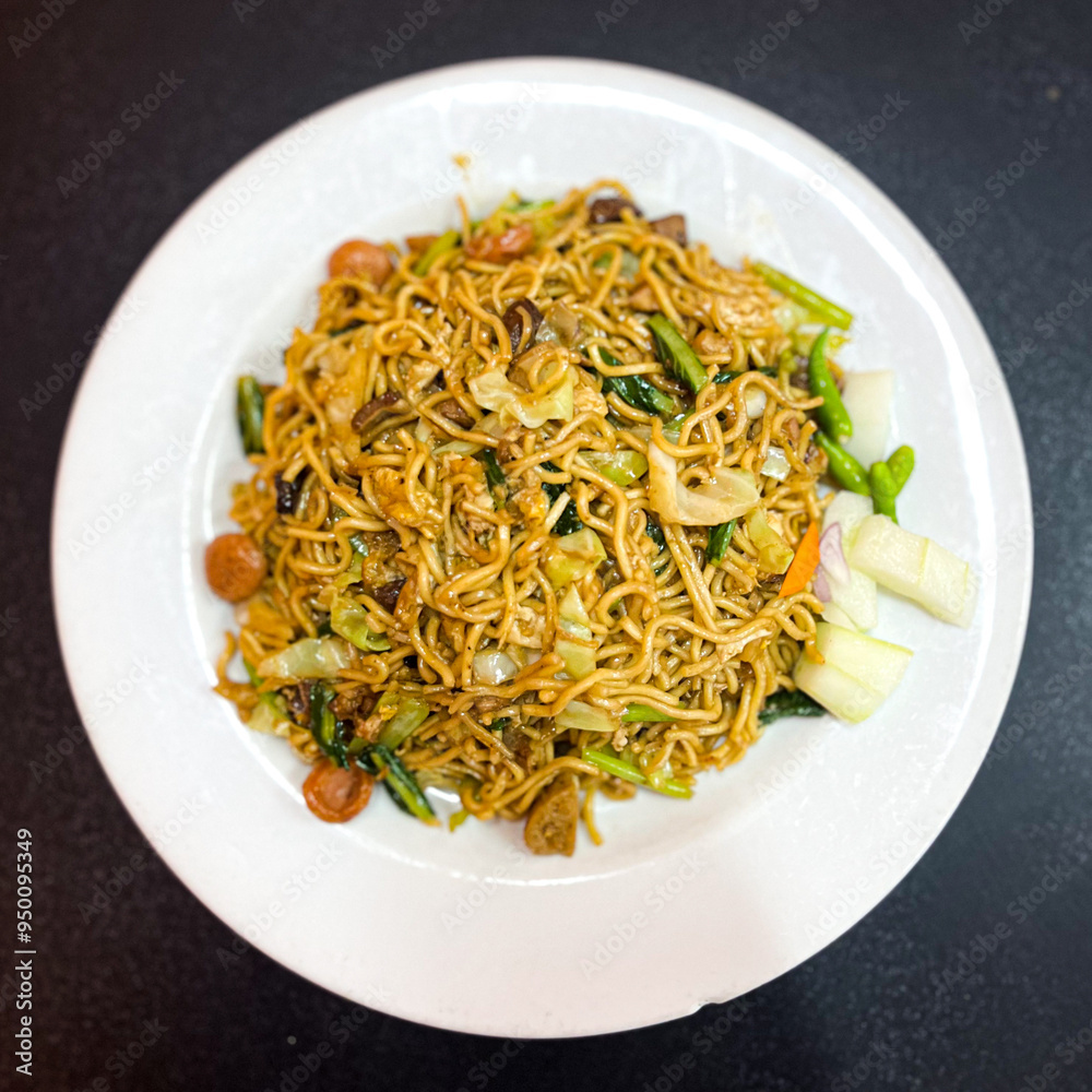 Stir-Fry Noodles with vegetables and pickle served on white plate and black background Stir-Fry Noodles with vegetables and pickle served on white plate and black background