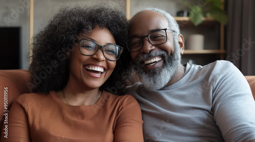 Smiling elderly African American couple sitting close together on a couch, radiating warmth and happiness. A beautiful moment of love and connection in their home.