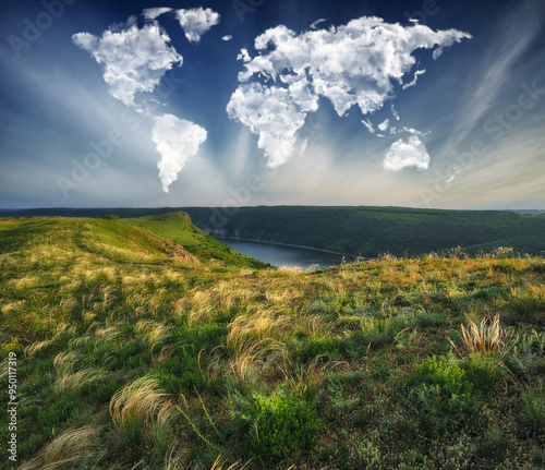 clouds in the form of a world map over a picturesque river. travel and landscape concept. spring meadow