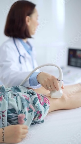 Doctor and kid patient. Orthopedist performing ultrasound examination on a child's knee in a clinic. Medicine and health care photo