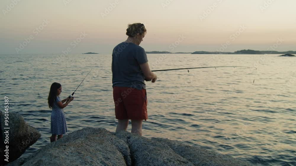 A mother and her little girl enjoy an evening of fishing on a rocky ocean shore at twilight. The post-sunset glow and the sound of the waves create a peaceful setting. A mother and her little girl enjoy an evening of fishing on a rocky ocean shore at twilight. The post-sunset glow and the sound of the waves create a peaceful setting.