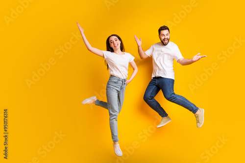 Full length photo of lovely young guy girl jump playful have fun dressed stylish white garment isolated on yellow color background