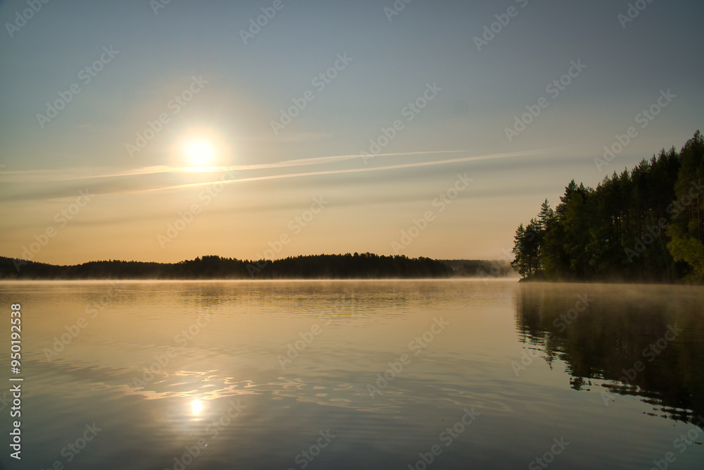 Sunrise over a Swedish lake with mirror-smooth water in front of trees on the shore Sunrise over a Swedish lake with mirror-smooth water in front of trees on the shore