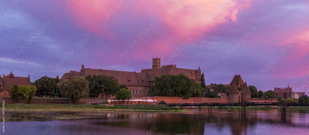 The Teutonic Castle in Malbork on the Nogat River during sunset The Teutonic Castle in Malbork on the Nogat River during sunset