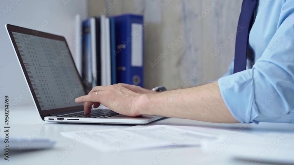 Businessman with blue t-shirt is working on his laptop, typing on the keyboard in the office. Business people concept Businessman with blue t-shirt is working on his laptop, typing on the keyboard in the office. Business people concept