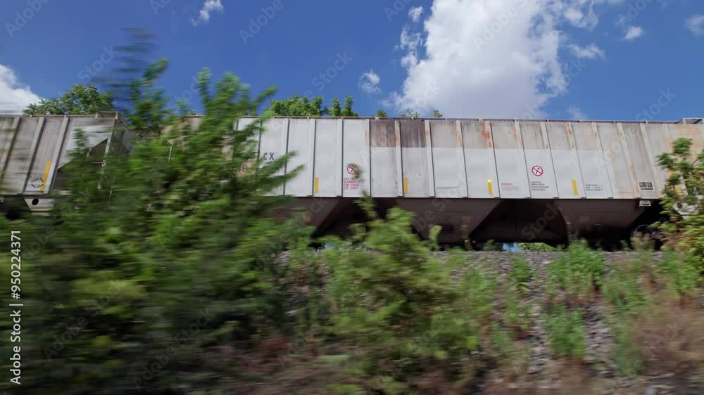 Driving alongside moving freight train and industrial railroad tracks to push industry and supply forward in the midwest part of the United States Driving alongside moving freight train and industrial railroad tracks to push industry and supply forward in the midwest part of the United States